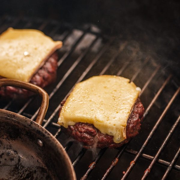Juicy beef burgers with melting cheese on a bbq