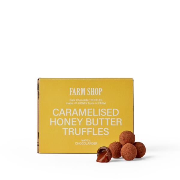 Box of honey truffles with loose truffles in front of the box and caramel filling showing