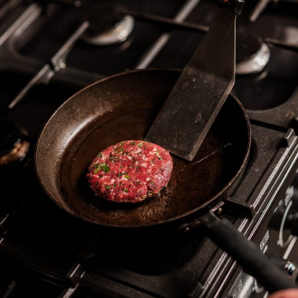 Lamb burger in a frying pan on a stove